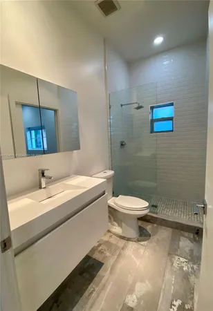 a bathroom with a granite countertop toilet a sink and mirror