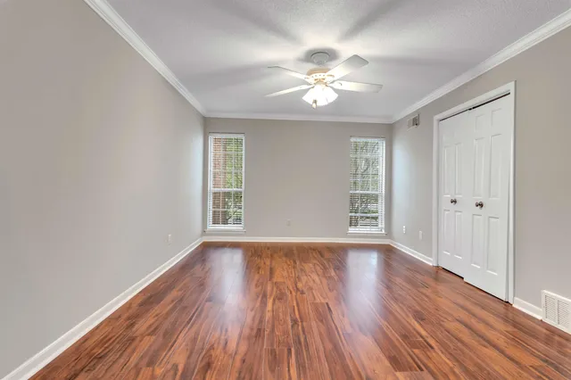 a view of an empty room with wooden floor and a window