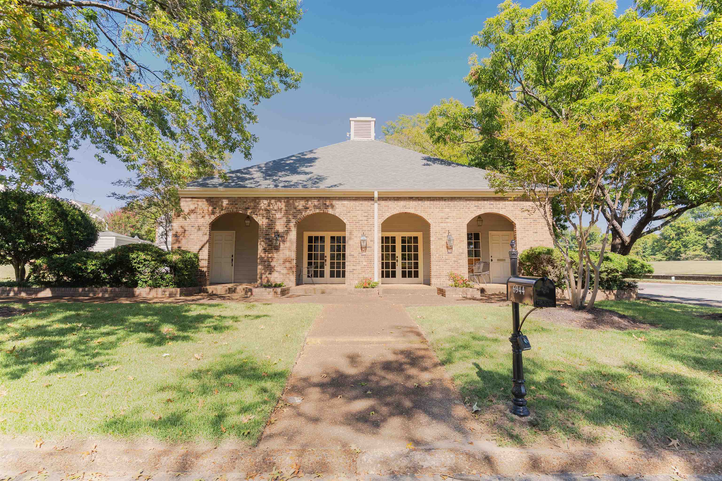 6942 Amberly Road, Unit 6942 Memphis, TN 38119 - Photo 31 of 32 a view of a white house with a yard and lawn chairs under a large tree