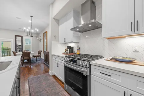 a kitchen with stainless steel appliances granite countertop a stove white cabinets a dining table and chairs