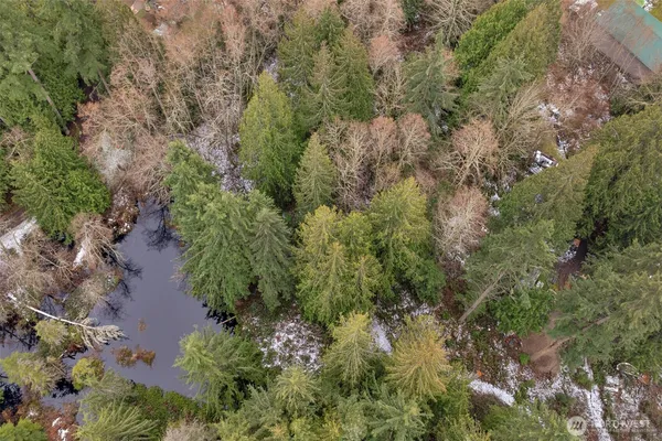an aerial view of residential house with outdoor space and trees all around