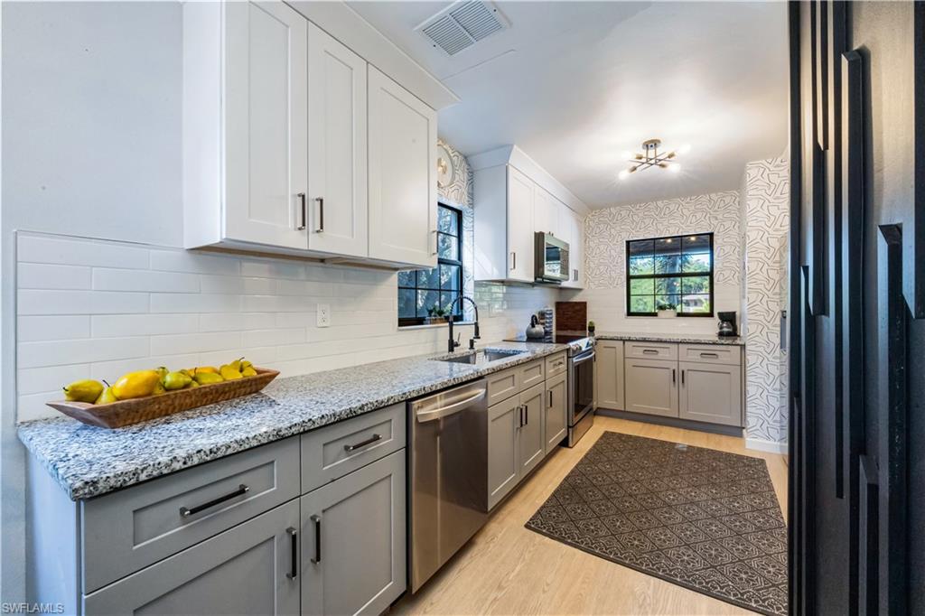 5238 Treetops Drive, Unit L201 Naples, FL 34113 - Photo 13 of 34 a kitchen with granite countertop a sink a stove and cabinets