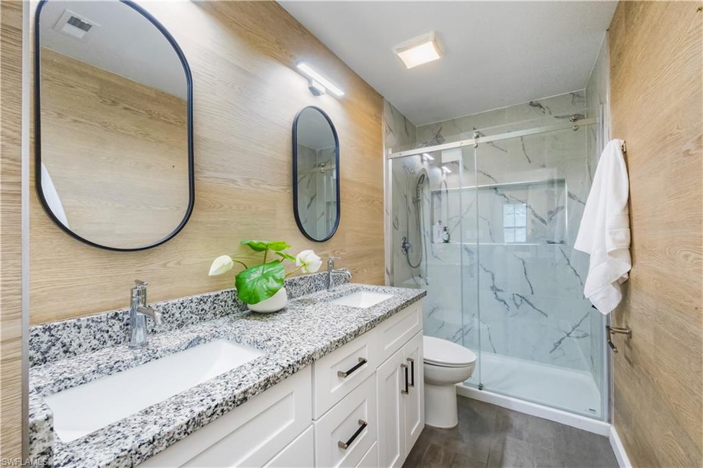 5238 Treetops Drive, Unit L201 Naples, FL 34113 - Photo 20 of 34 a bathroom with a granite countertop sink mirror and a shower