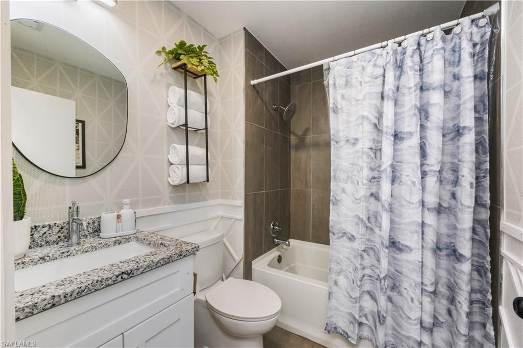 5238 Treetops Drive, Unit L201 Naples, FL 34113 - Photo 24 of 34 a bathroom with a granite countertop sink a toilet and a mirror