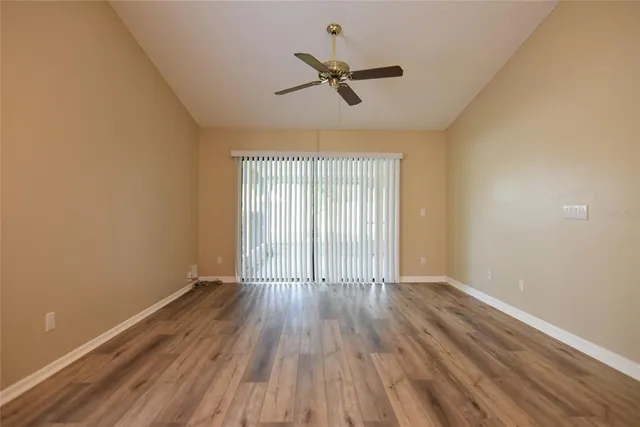 an empty room with wooden floor fan and windows