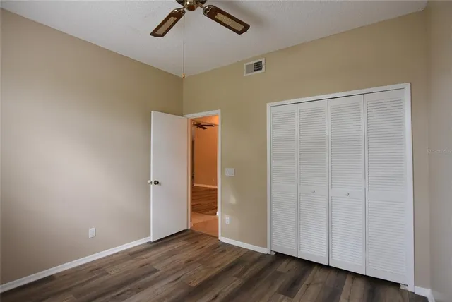 an empty room with wooden floor closet and windows