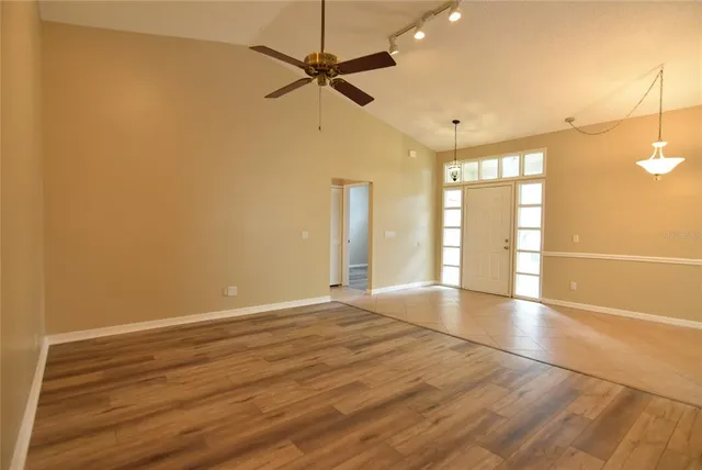 an empty room with wooden floor fan and windows