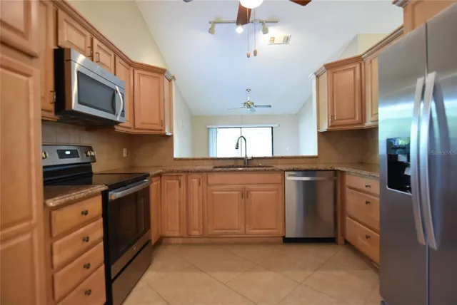 a kitchen with stainless steel appliances granite countertop a refrigerator a stove top oven a sink and dishwasher