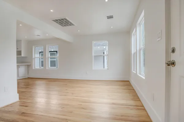 a view of an empty room with a window and wooden floor