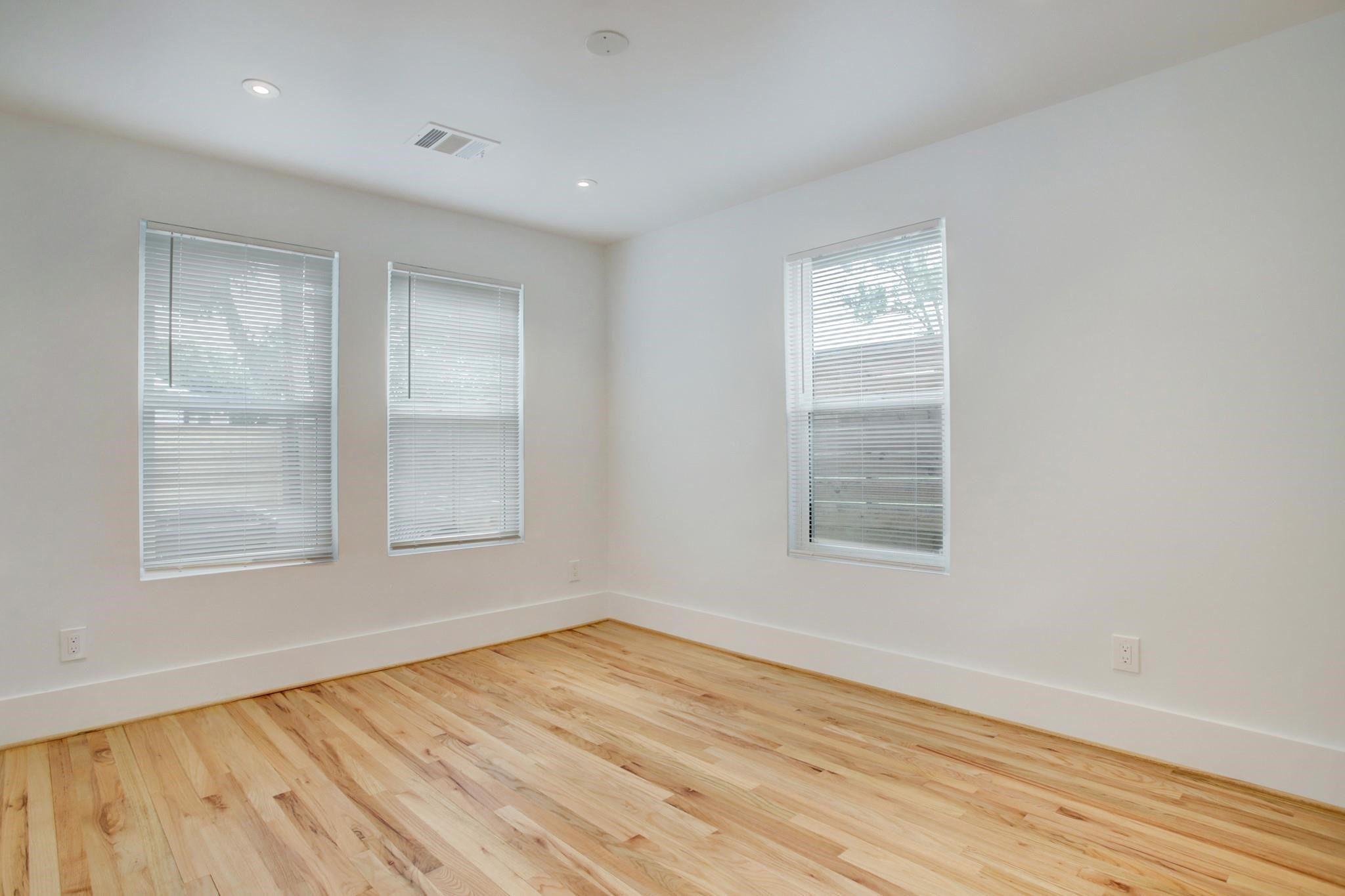 6107 North Main Street Houston, TX 77008 - Photo 8 of 14 an empty room with wooden floor and windows