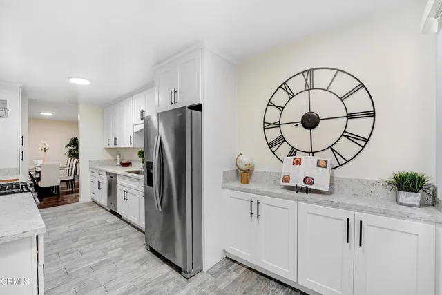 a kitchen with stainless steel appliances granite countertop a refrigerator a stove and a wooden floors