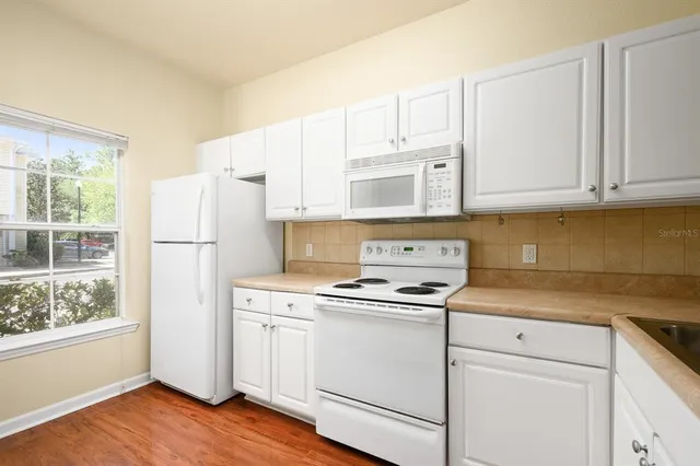 a kitchen with stainless steel appliances granite countertop a sink and cabinets with wooden floor