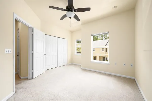 an empty room with windows and ceiling fan