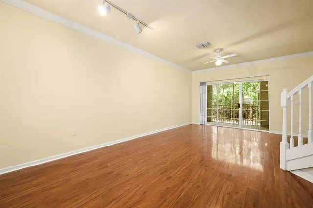 a view of empty room with wooden floor and fan