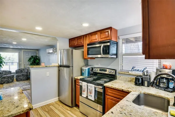a kitchen with stainless steel appliances granite countertop a refrigerator a stove top oven a sink dishwasher and white cabinets with wooden floor
