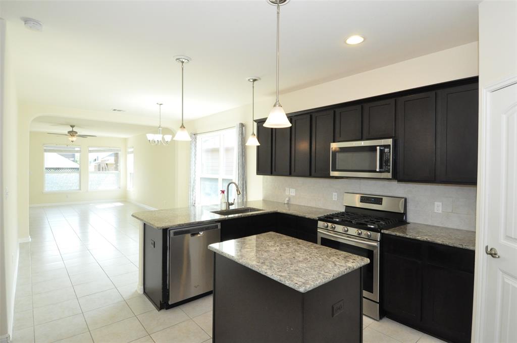 3451 Mayfield Ranch Boulevard, Unit 610 Round Rock, TX 78681 - Photo 19 of 19 Kitchen with appliances with stainless steel finishes, pendant lighting, a center island, open floor plan, and light stone counters