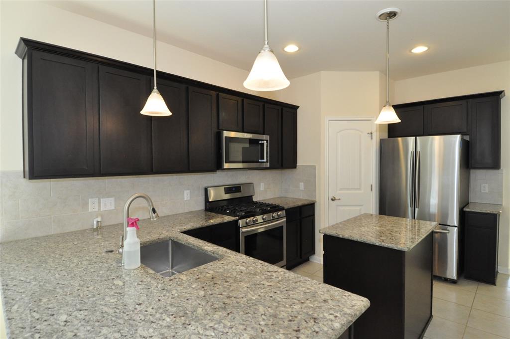 3451 Mayfield Ranch Boulevard, Unit 610 Round Rock, TX 78681 - Photo 3 of 19 Kitchen featuring a kitchen island, appliances with stainless steel finishes, backsplash, pendant lighting, and light tile patterned floors