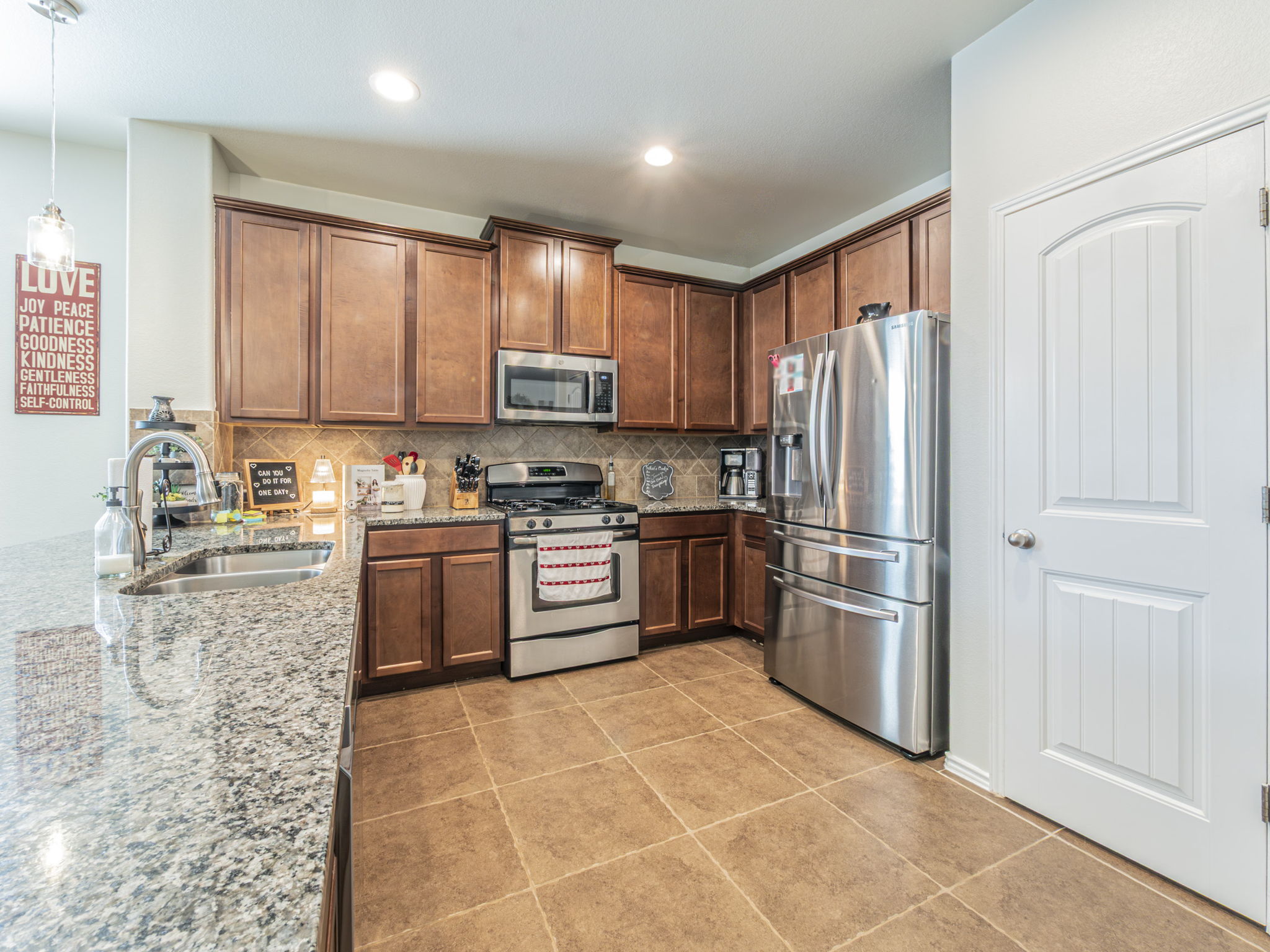 1366 Heep Run Buda, TX 78610 - Photo 4 of 37 Kitchen featuring light stone countertops, stainless steel appliances, hanging light fixtures, tasteful backsplash, and light tile patterned floors