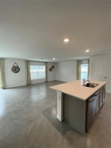 a large kitchen with a large counter top a sink a stove a refrigerator and cabinets