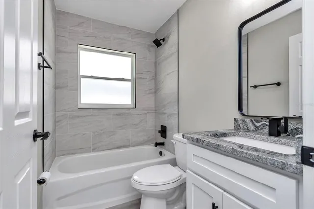 a bathroom with a granite countertop toilet a sink and a bathtub