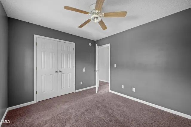 an empty room with a window and a ceiling fan