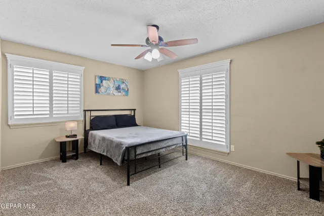 a view of a white house next to a yard with plants and brick wall