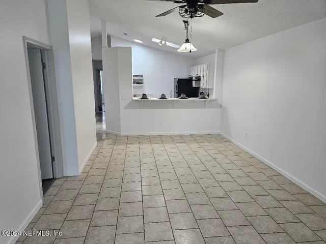 a view of an empty room and chandelier fan