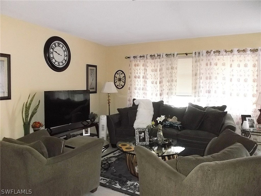 203 Davis Road Lehigh Acres, FL 33936 - Photo 3 of 10 a living room with furniture a window and a flat screen tv