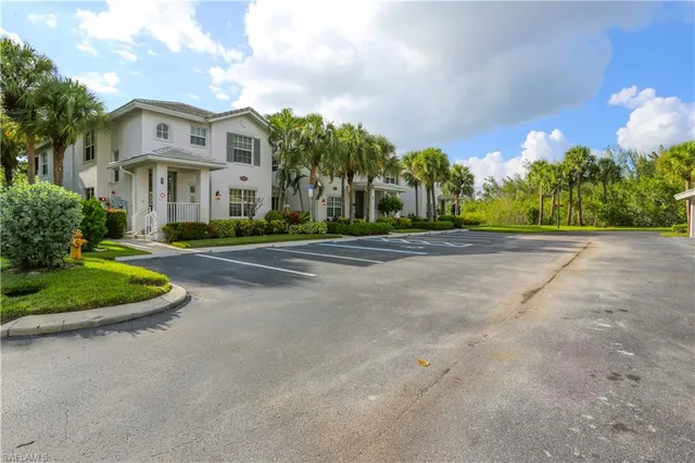 a view of a white house with a big yard and potted plants