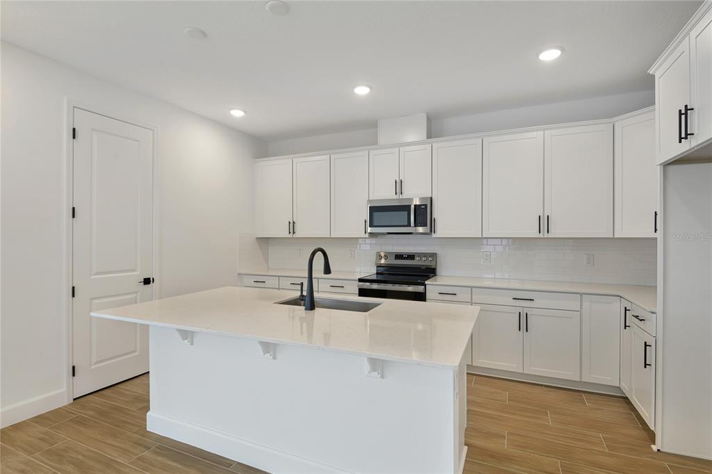 145 Waterstone Loop Tavares, FL 32778 - Photo 6 of 16 a kitchen with kitchen island granite countertop a sink a stove and cabinets