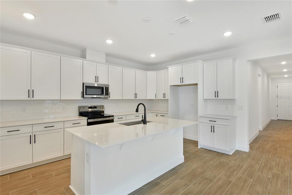 145 Waterstone Loop Tavares, FL 32778 - Photo 7 of 16 a kitchen with kitchen island white cabinets white stainless steel appliances and sink