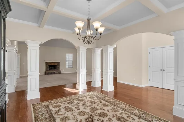 a view of a big room with wooden floor a chandelier a flat screen tv and fireplace