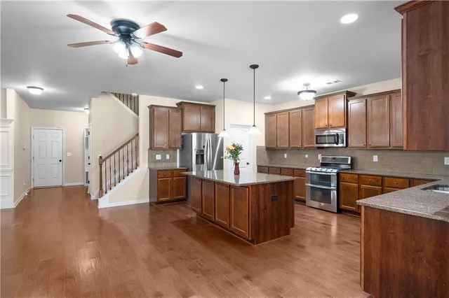a large kitchen with stainless steel appliances lots of counter space and wooden floor