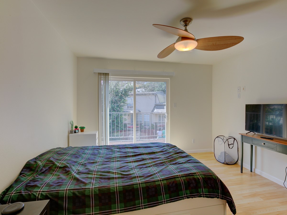 710 Castle Ridge Road, Unit B Austin, TX 78746 - Photo 17 of 27 A well-lit bedroom features hardwood floors and a sliding glass door leading to a private balcony.