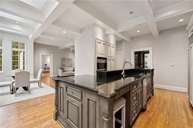 a kitchen with stainless steel appliances granite countertop a refrigerator a stove a sink and white cabinets with wooden floor