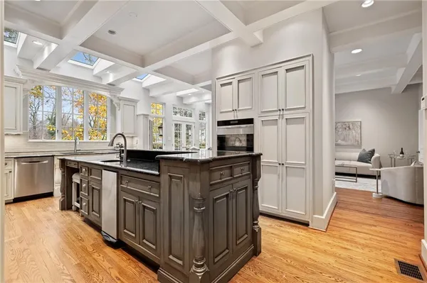 a kitchen with stainless steel appliances granite countertop a refrigerator a sink dishwasher a stove and white cabinets with wooden floor