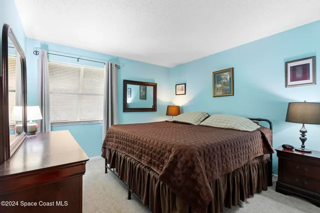 a bedroom with a bed a dresser and next to a window