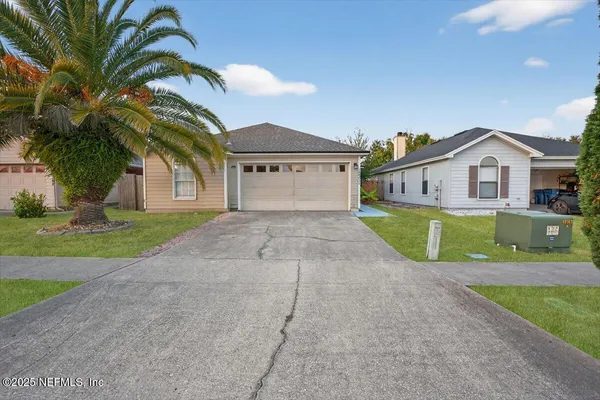 a view of a house with a small yard and palm trees