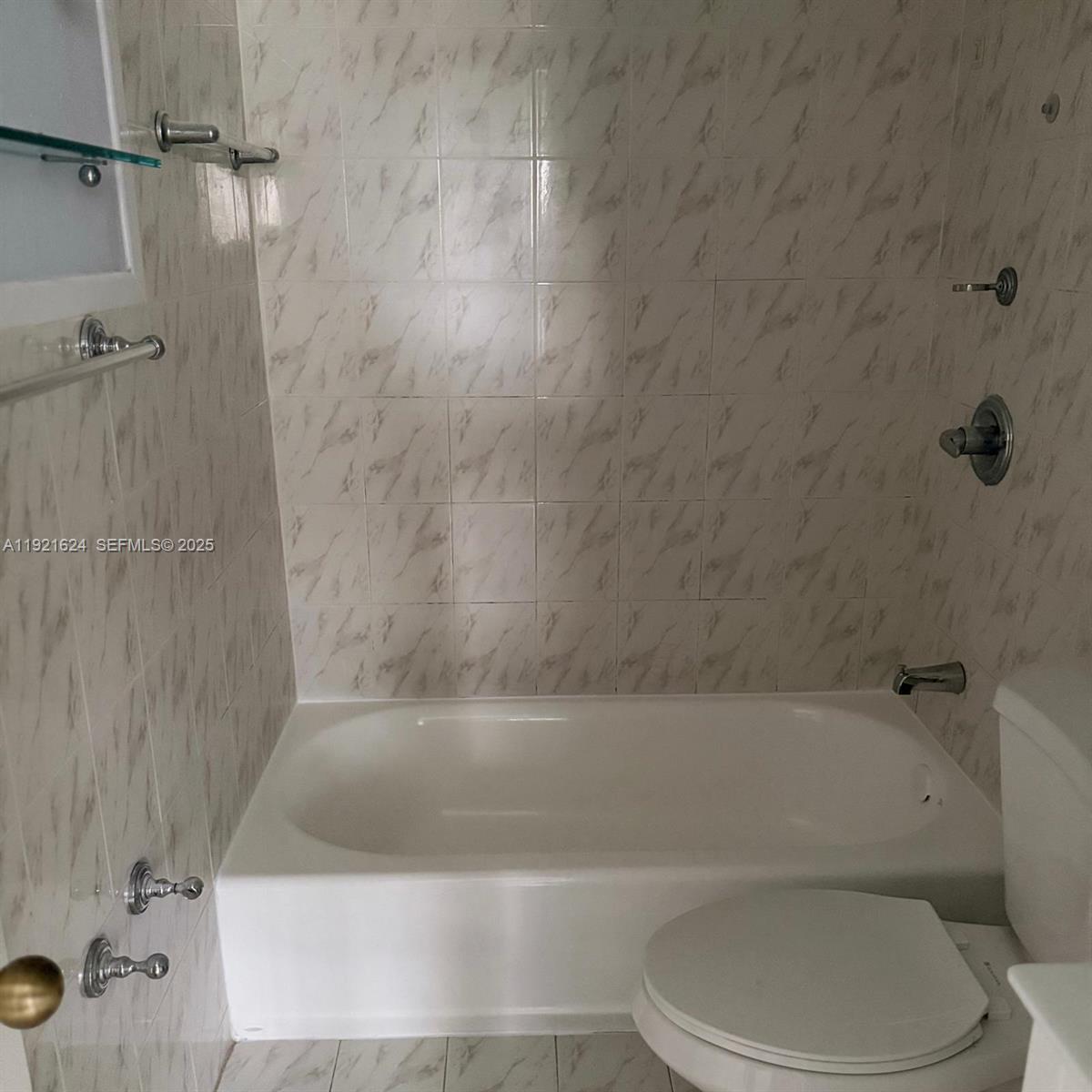 5501 Northwest 7th Street, Unit E301 Miami, FL 33126 - Photo 18 of 28 a white bath tub sitting next to a toilet