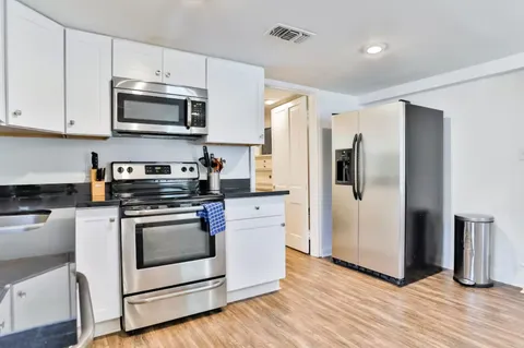 a kitchen with stainless steel appliances a white refrigerator a stove a microwave and cabinets