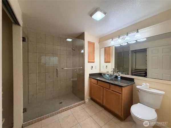 a bathroom with a granite countertop sink a toilet a mirror and shower