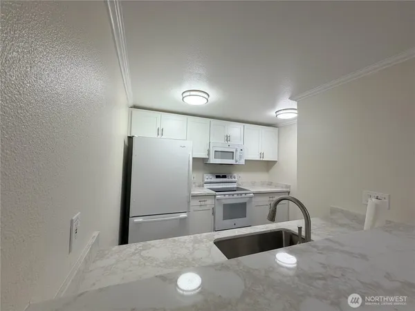a kitchen with stainless steel appliances a refrigerator sink and white cabinets