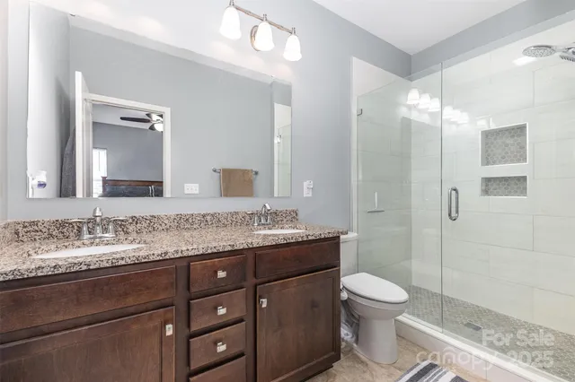 a bathroom with a granite countertop sink toilet a mirror and shower