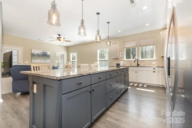 a large kitchen with kitchen island granite countertop a large center island a sink stainless steel appliances and cabinets