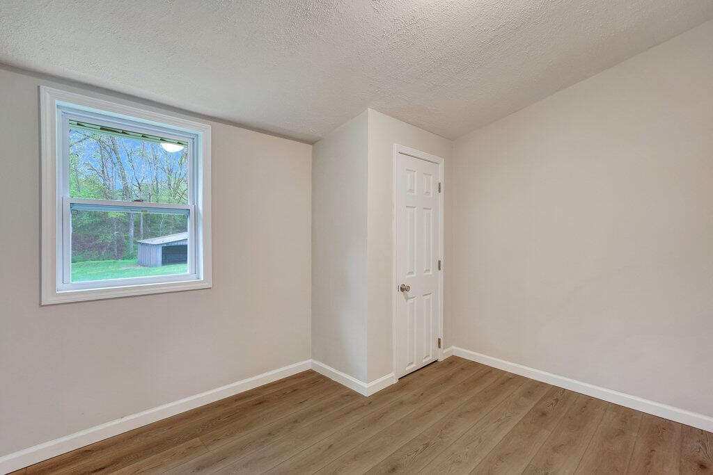 183 Earl Ezell Road Spring City, TN 37381 - Photo 13 of 30 a view of an empty room with wooden floor and a window