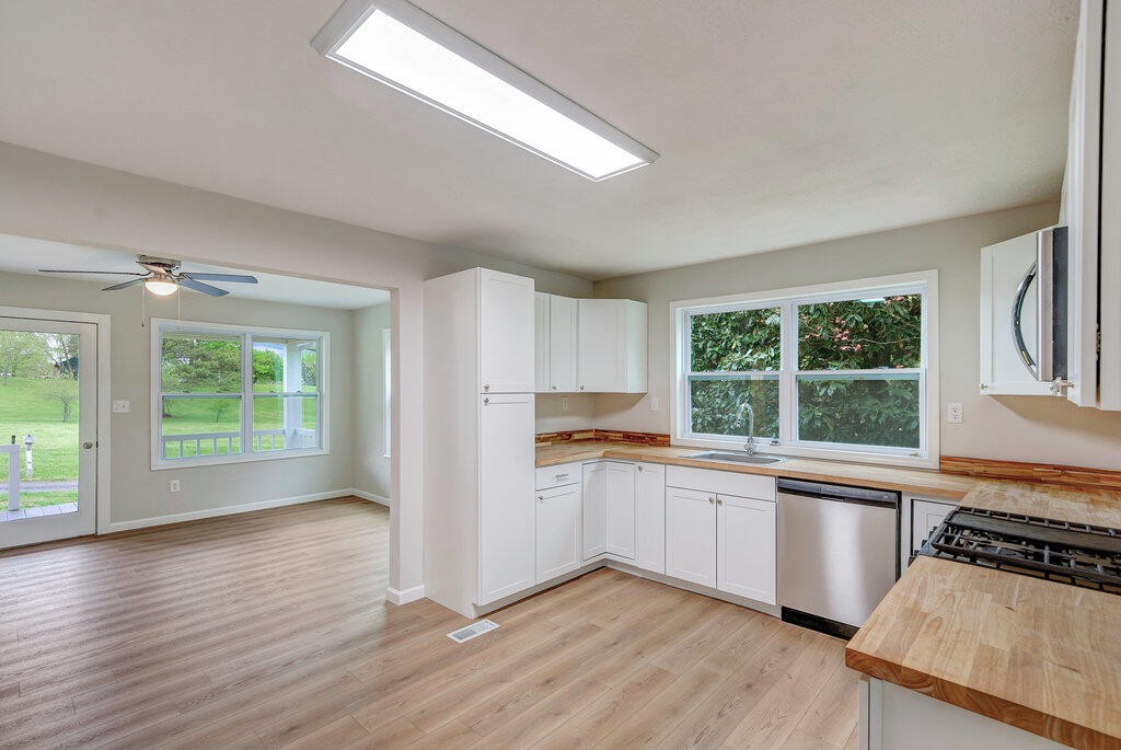 183 Earl Ezell Road Spring City, TN 37381 - Photo 8 of 30 a kitchen with stainless steel appliances a stove a sink and white cabinets with wooden floor