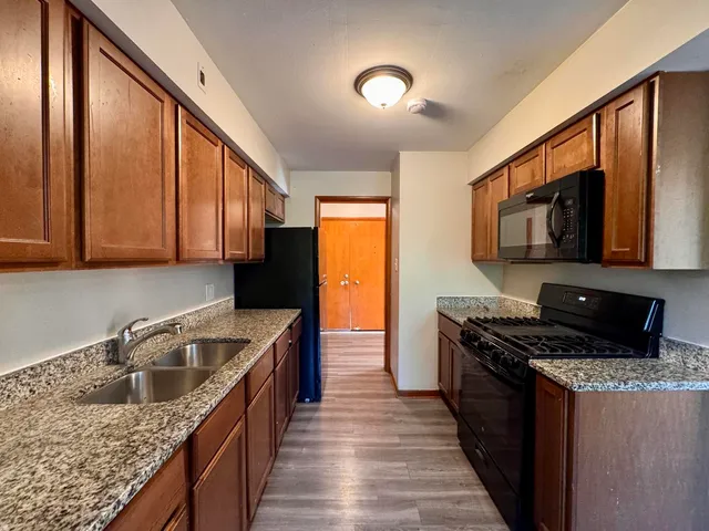 a kitchen with stainless steel appliances granite countertop a stove a sink and a microwave