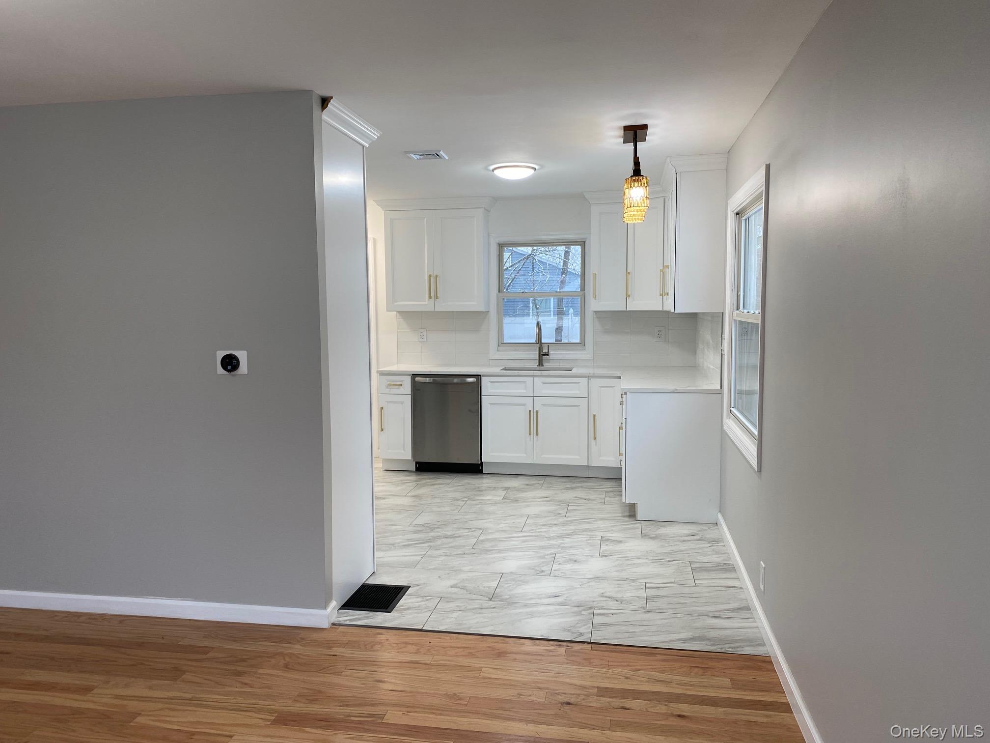 5 Smith Road Cornwall, NY 12518 - Photo 15 of 32 Kitchen featuring white cabinets, light wood-type flooring, dishwasher, hanging light fixtures, and backsplash