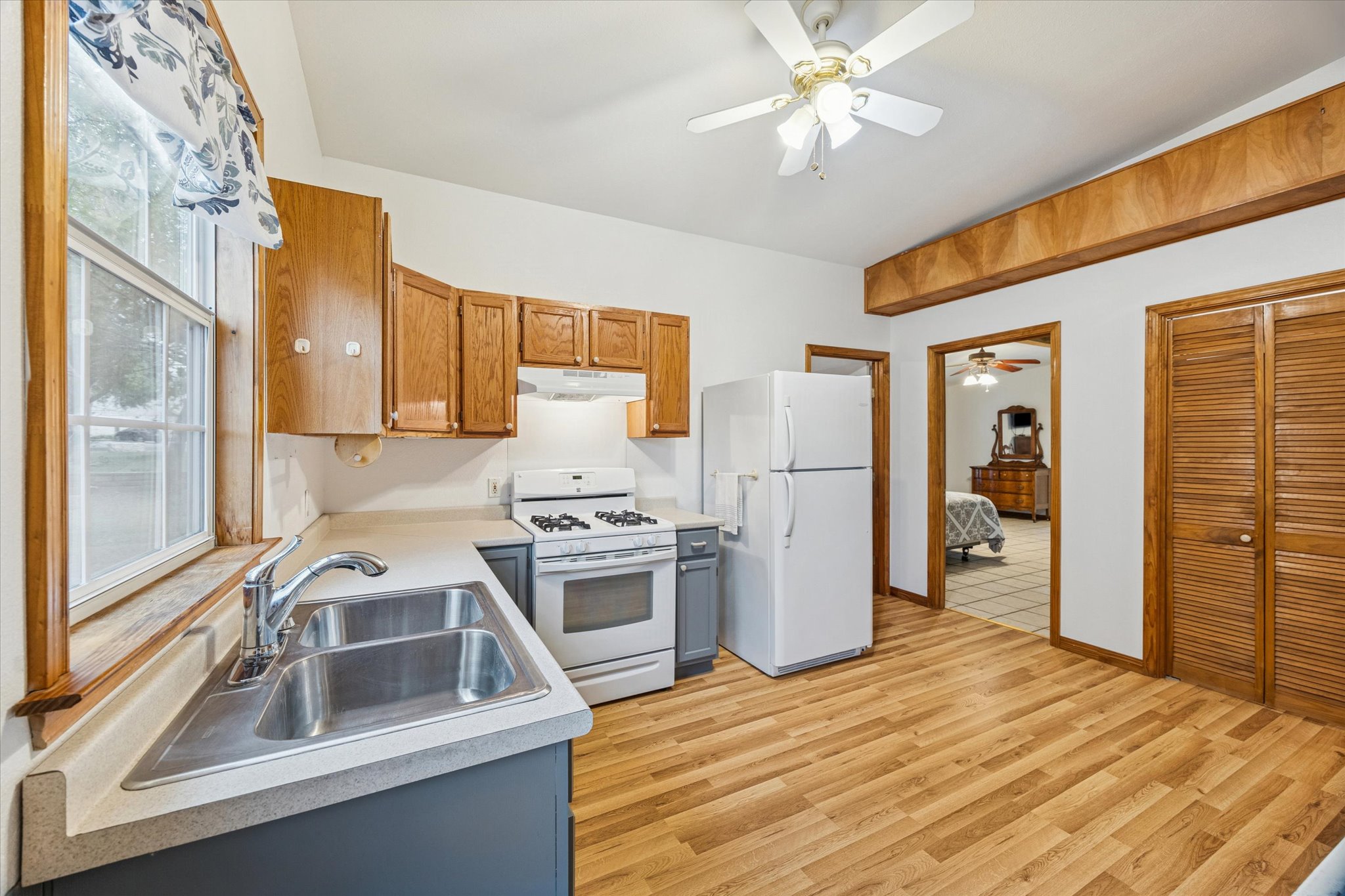 3502 1869th Ranch Liberty Hill, TX 78642 - Photo 12 of 18 Kitchen featuring white appliances, light countertops, light wood finished floors, under cabinet range hood, and brown cabinets