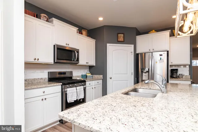 a kitchen with stainless steel appliances granite countertop a refrigerator sink stove microwave and cabinets